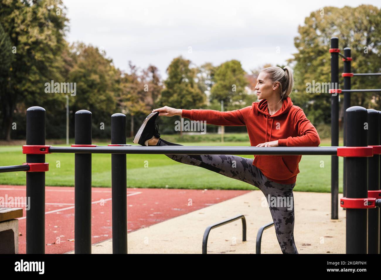 Jeune sportswoman faisant de l'exercice d'étirement devant la barre horizontale Banque D'Images
