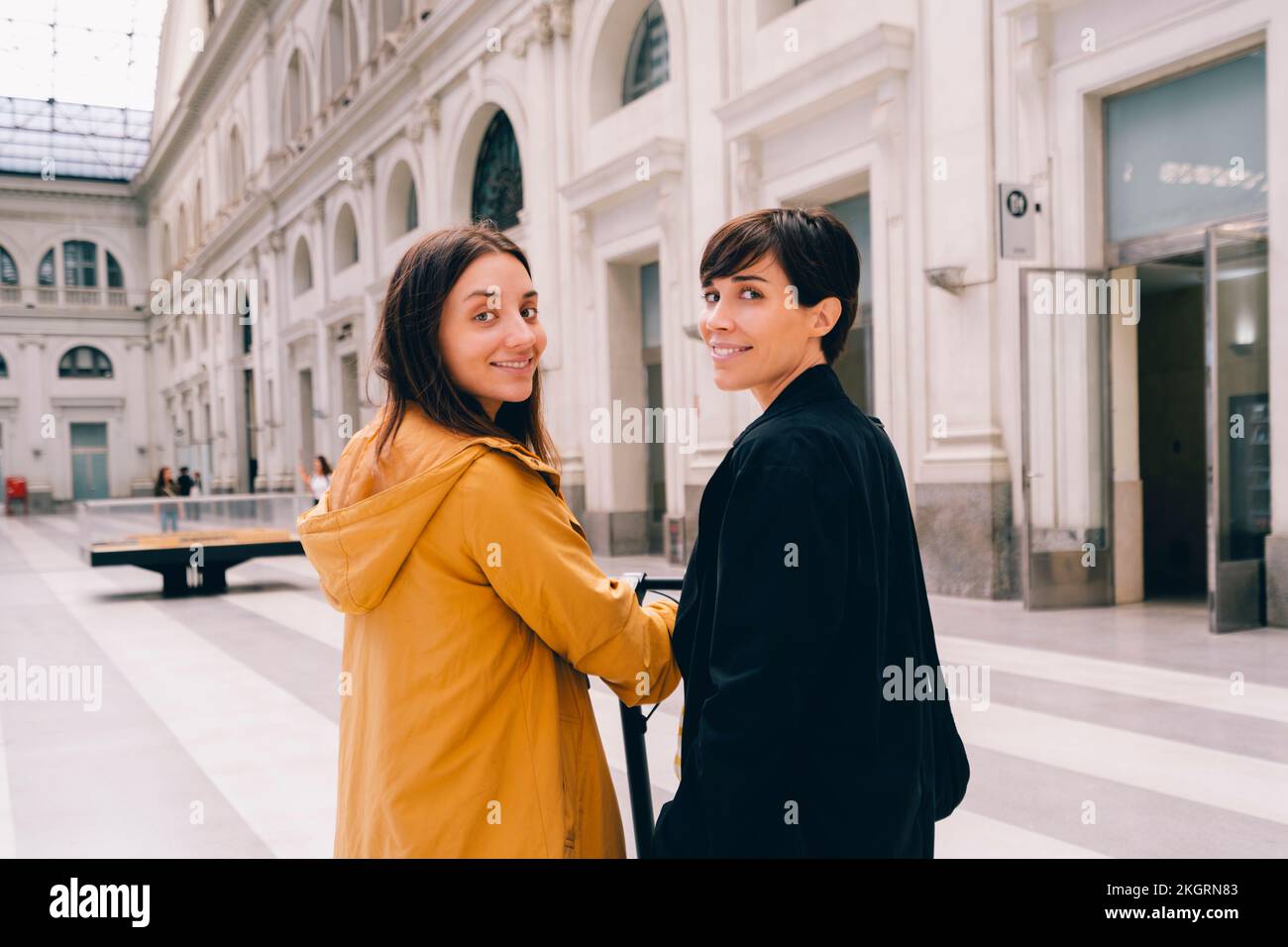 Jeune femme souriante avec un ami dans un bâtiment urbain Banque D'Images