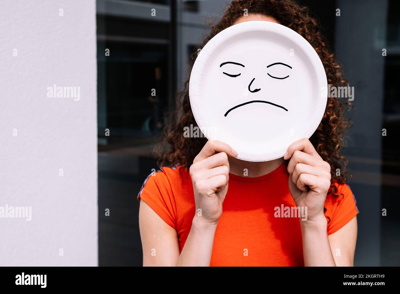 Jeune femme tenant une plaque d'émoticône triste sur le visage Banque D'Images
