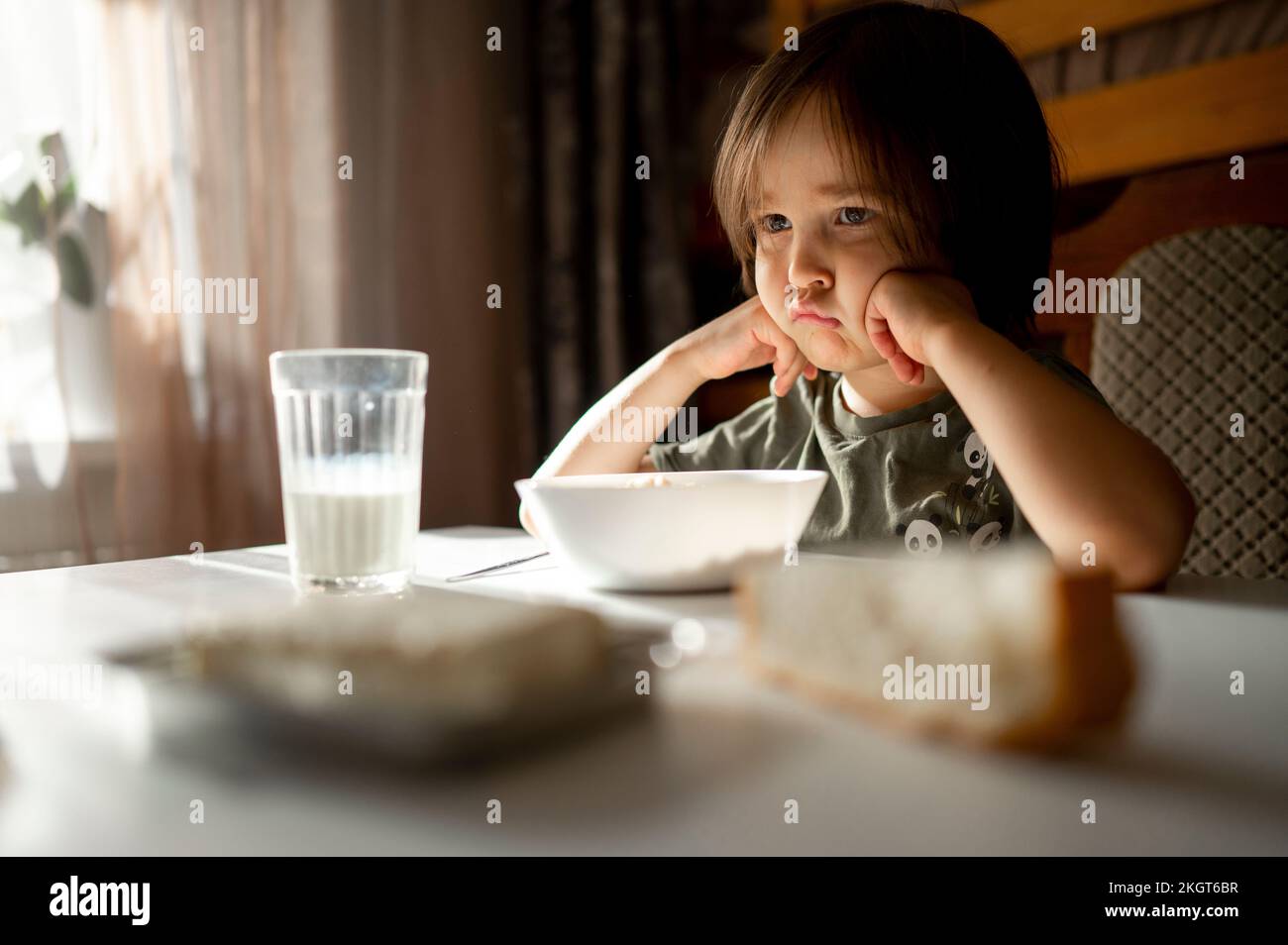 Mécontent garçon avec de la nourriture sur la table à manger à la maison Banque D'Images