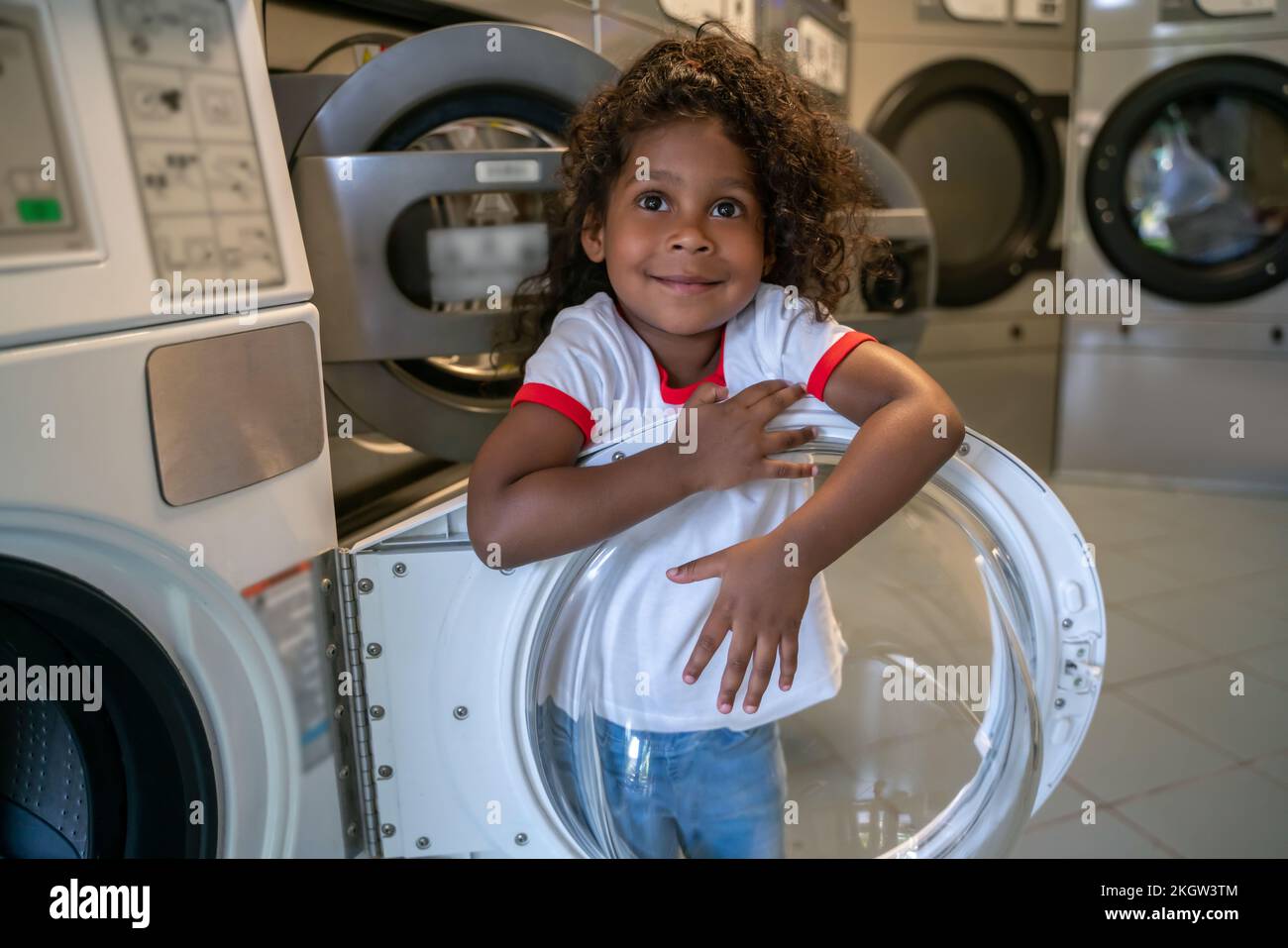 Enfant heureux jouant dans une laverie publique Banque D'Images