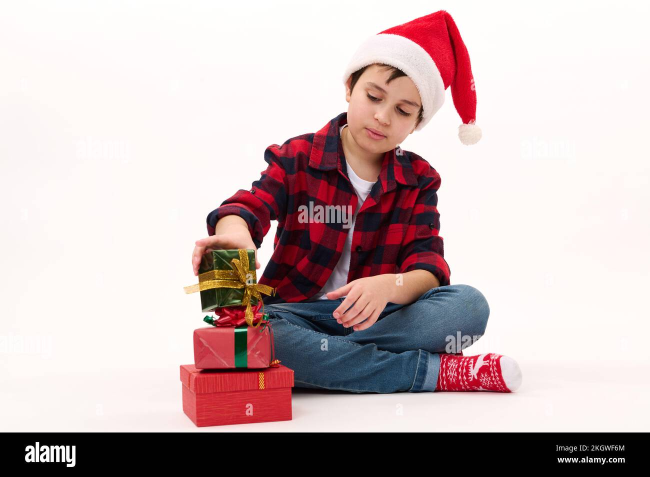 Joyeux enfant garcon en chapeau de pere Noel chemise a carreaux rouges et chaussettes avec motif de Noel piles cadeaux un sur un. Arriere plan blanc Photo Stock Alamy