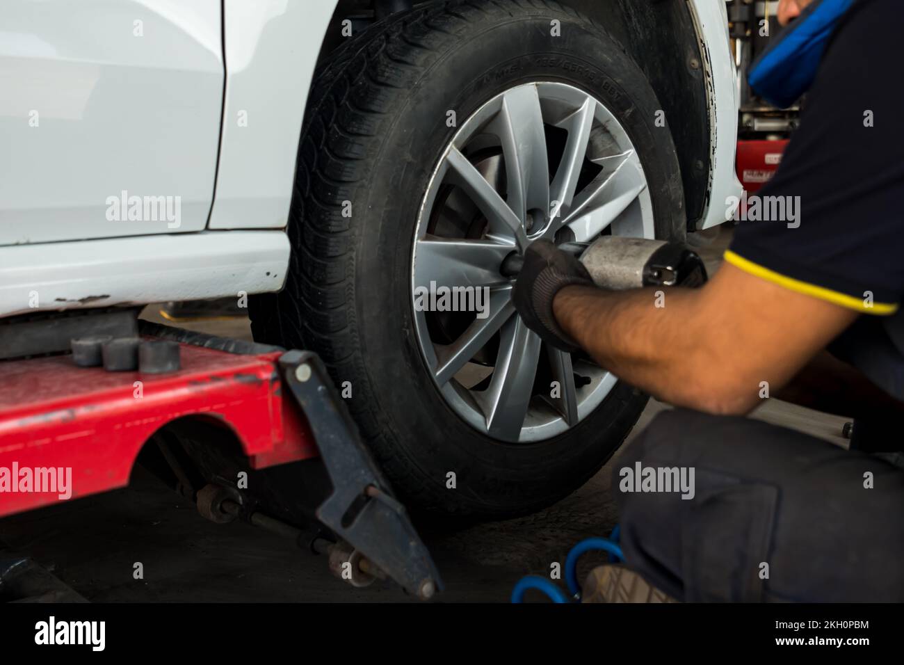 Auto mécanicien homme avec un tournevis électrique changer le pneu à l'extérieur. Service de voiture. Concept d'installation des pneus. Banque D'Images