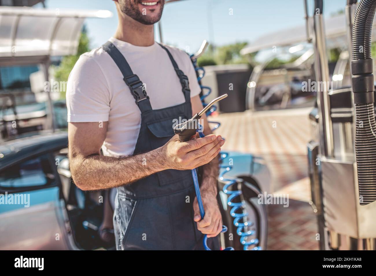 Un employé de station-service joyeux se préparant à une procédure de lavage de voiture client Banque D'Images