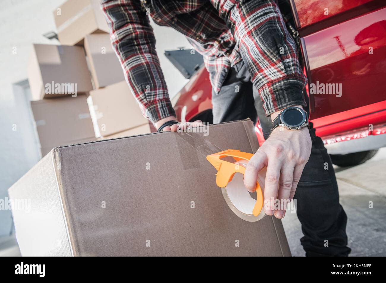 Travailleur de l'entreprise de déménagement fixation de la boîte en carton avec du ruban d'emballage transparent pour un transport sûr. Services professionnels de réinstallation. Banque D'Images Travailleur de l'entreprise de déménagement fixation de la boîte en carton avec du ruban d'emballage transparent pour un transport sûr. Services professionnels de réinstallation. Banque D'Images