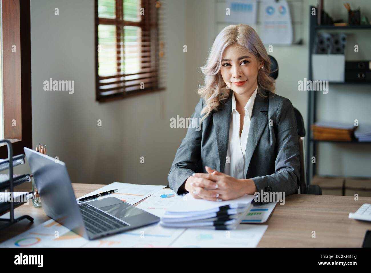 Portrait d'une femme propriétaire d'entreprise montrant un visage souriant heureux car il a investi avec succès son entreprise en utilisant des ordinateurs et le budget financier Banque D'Images