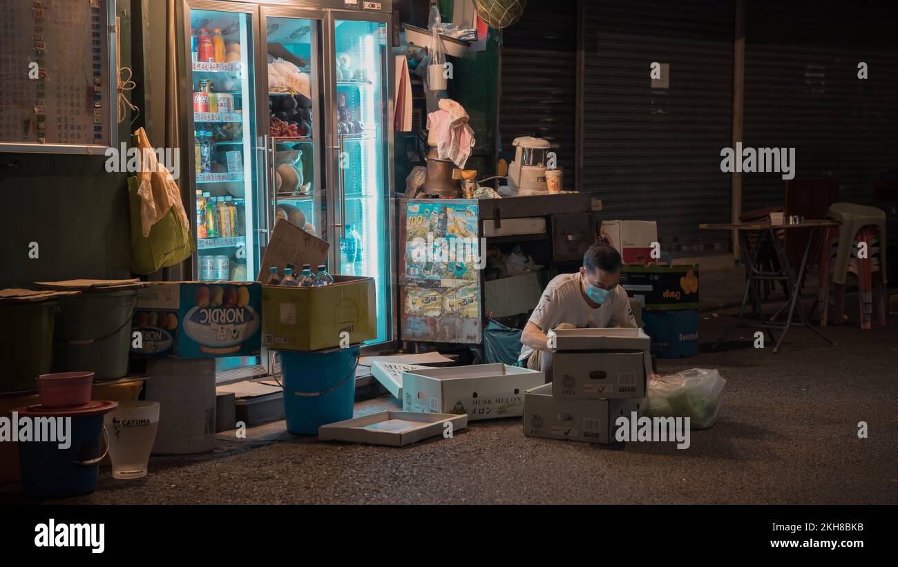Image horizontale d'un homme âgé qui ferme son magasin la nuit à Argyle Street, Mong Kok, Hong Kong Banque D'Images