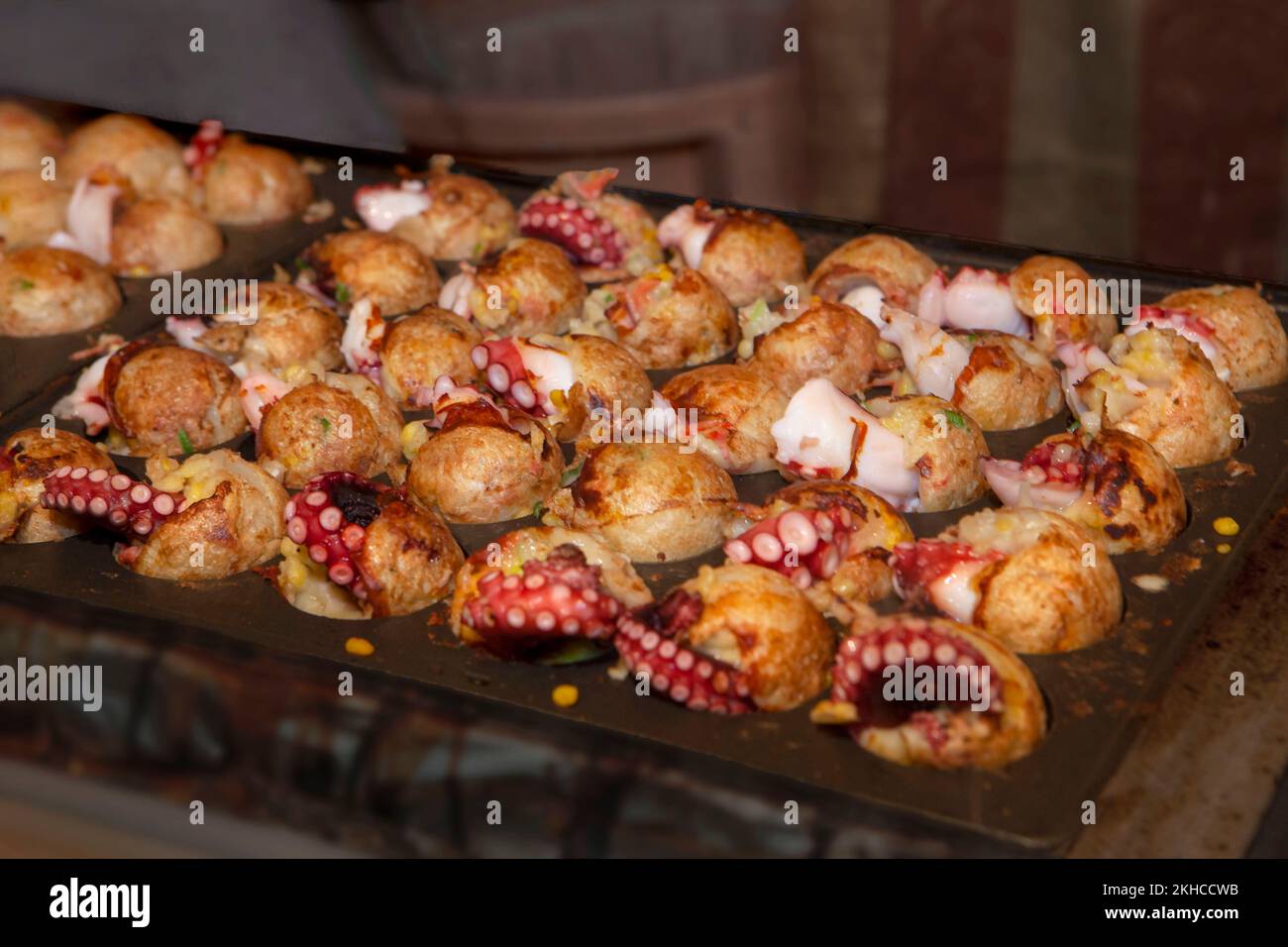 Le takoyaki japonais de la cuisine de rue, ou boulettes de viande de poulpe, cuisant dans un grand lot Banque D'Images