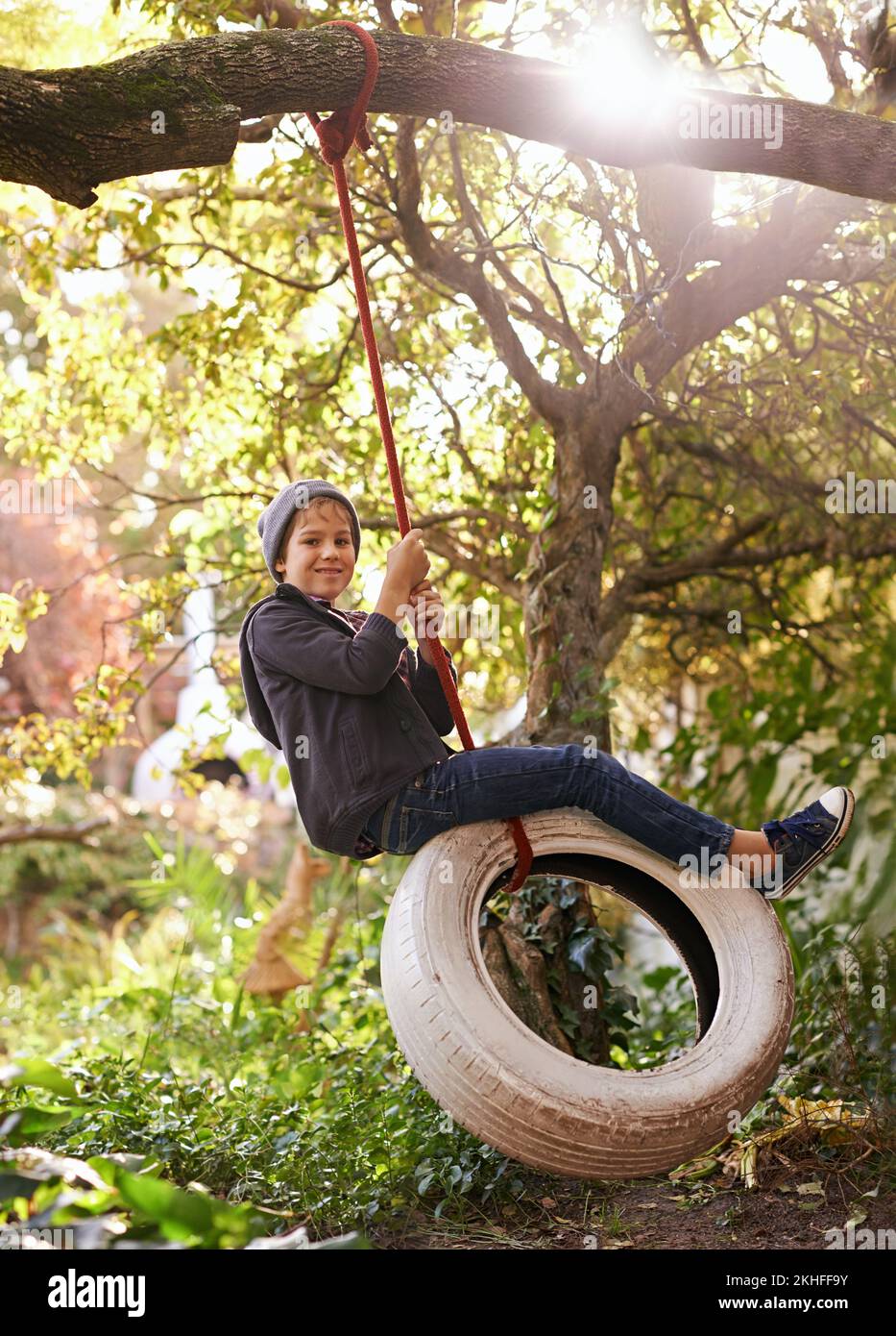 Des journées d'été insouciantes d'une enfance idyllique. Un préadolescent balançant sur une balançoire de pneu dans le jardin. Banque D'Images