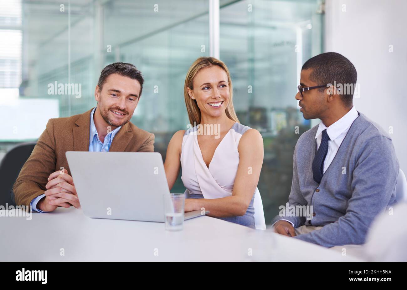 Satisfait de leurs résultats. un groupe diversifié de collègues utilisant un ordinateur portable au travail. Banque D'Images