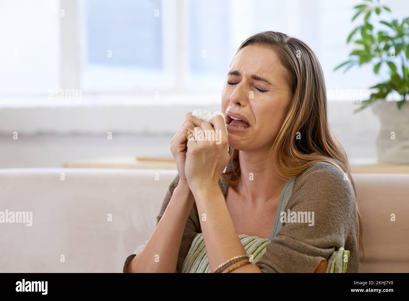 Aaah Chooooooo. une femme attrayante étant émotive à la maison. Banque D'Images