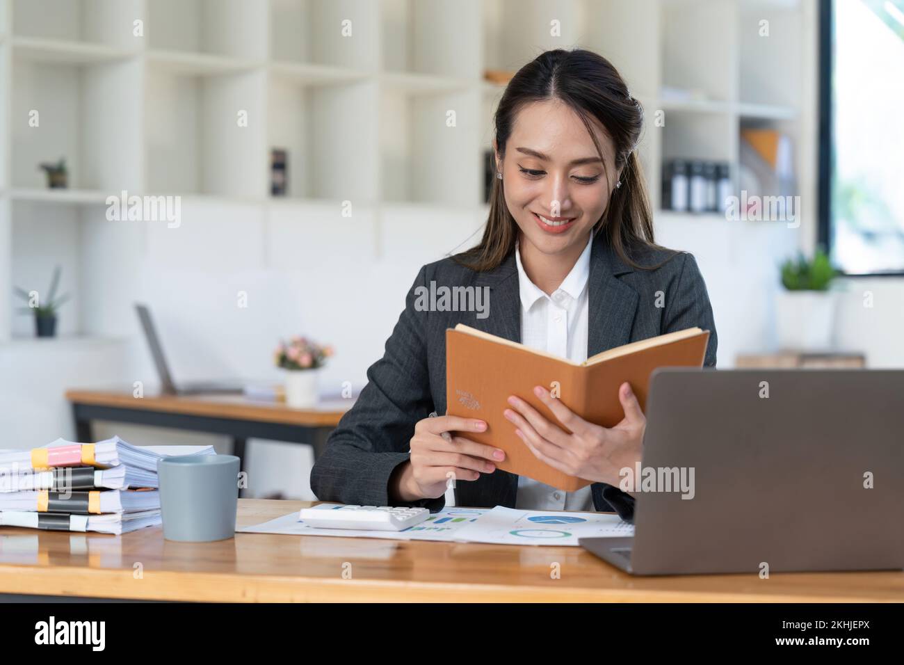 Souriant jeunes femmes d'affaires asiatiques travaillant avec la calculatrice, document d'affaires et ordinateur portable, inspecteur financier et secrétaire de fabrication Banque D'Images