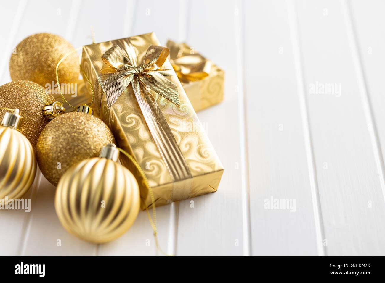 Deux cadeaux de noël en or et des boules de noël sur la table blanche. Banque D'Images