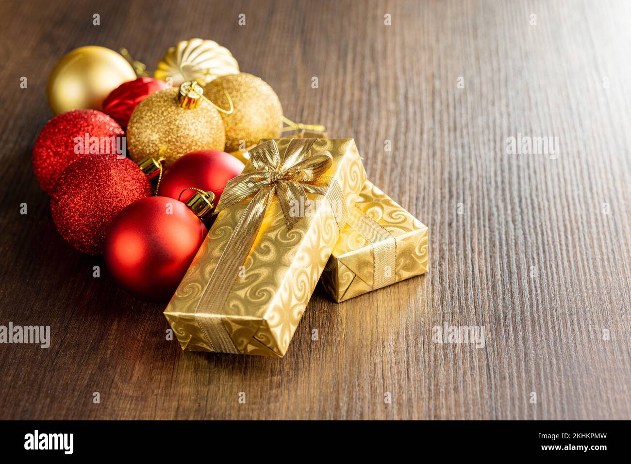 Deux cadeaux de noël en or et des boules de noël sur la table en bois. Banque D'Images