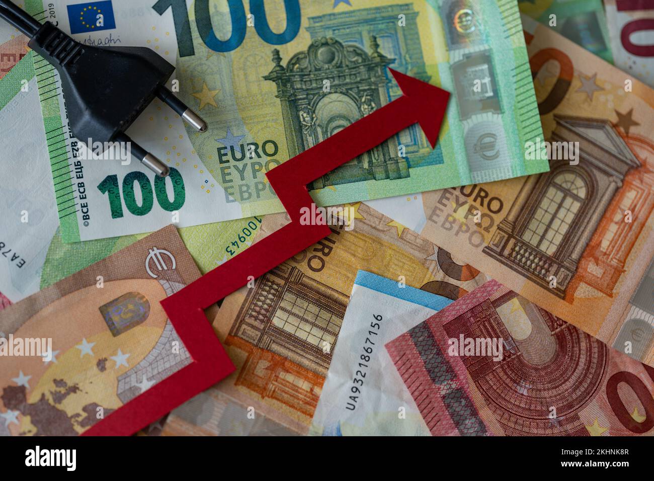 Une fiche électrique et une flèche rouge vers le haut sur les billets en euros - concept de la hausse des prix de l'électricité en Europe Banque D'Images