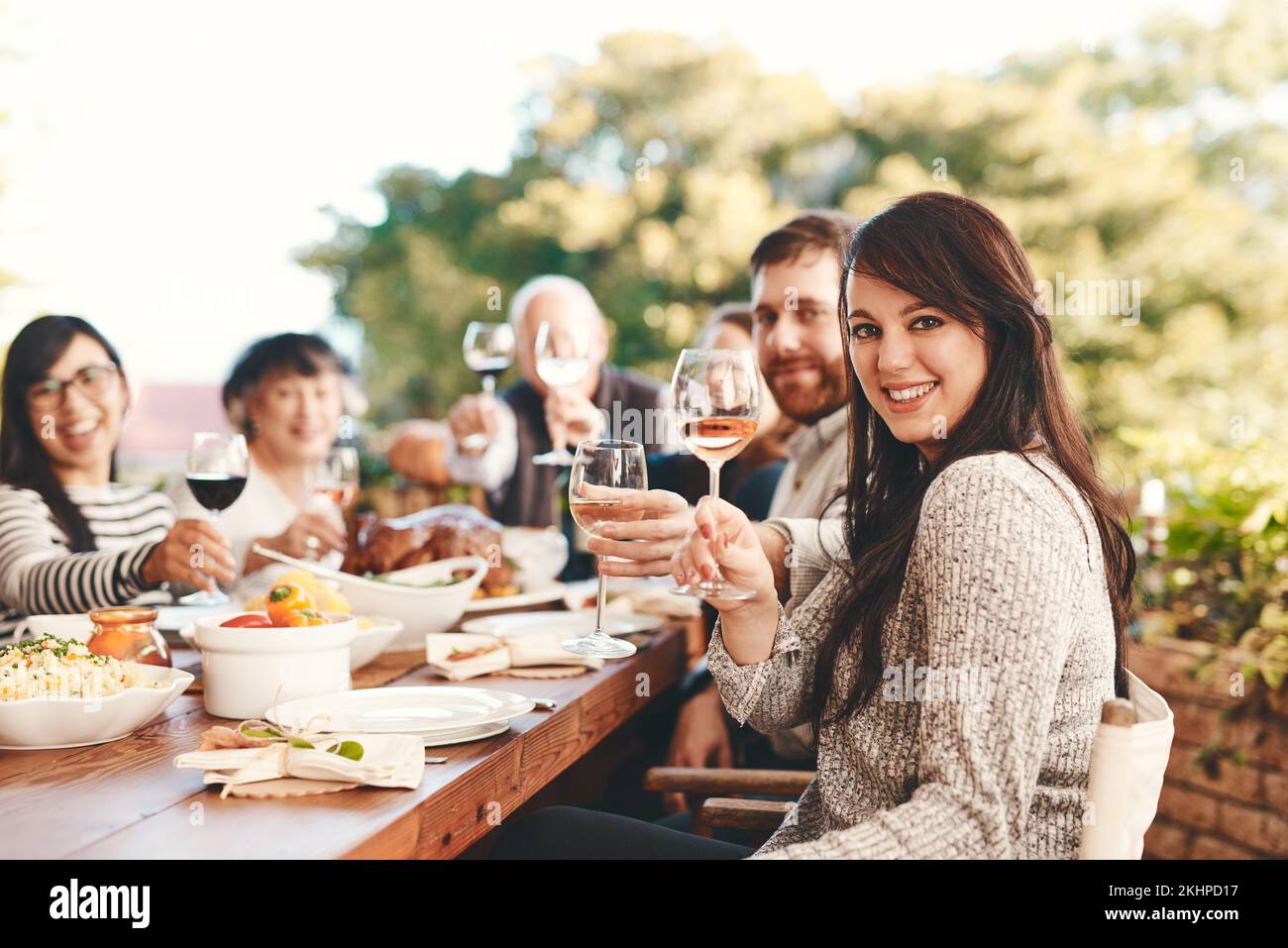 Toast, vin et famille au déjeuner dans un jardin lors d'une fête de Noël sur le patio. Nourriture, alcool et portrait d'amis avec une santé et manger à un Banque D'Images