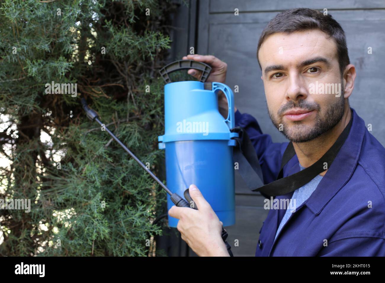 Jardinier en uniforme bleu tenant l'équipement de fumigation Banque D'Images