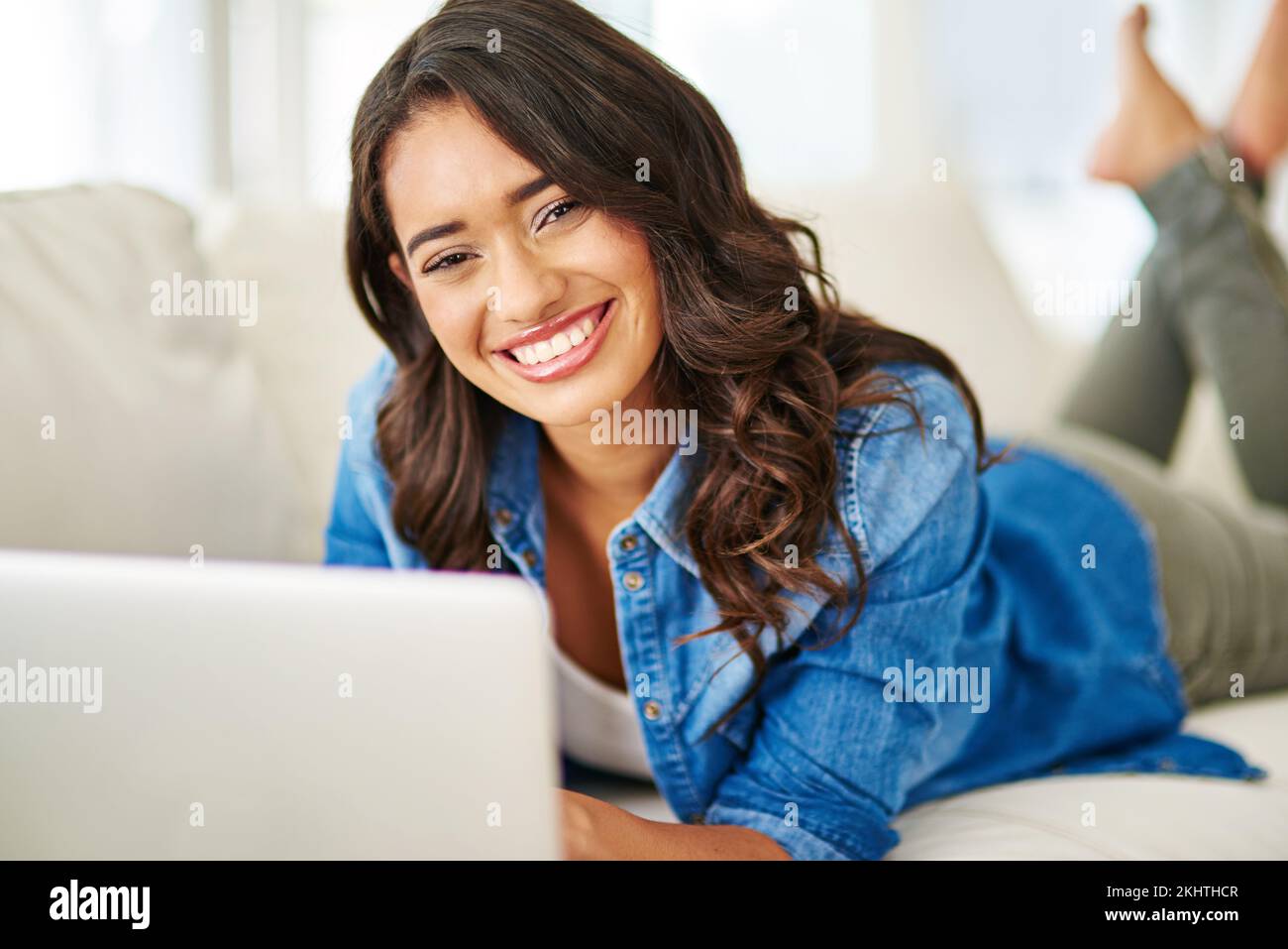 Femme, ordinateur portable et détendez-vous avec le sourire sur le canapé pour étudier, diffuser ou indépendant concepteur dans le travail à distance à la maison. Portrait d'une femme pigiste heureuse Banque D'Images