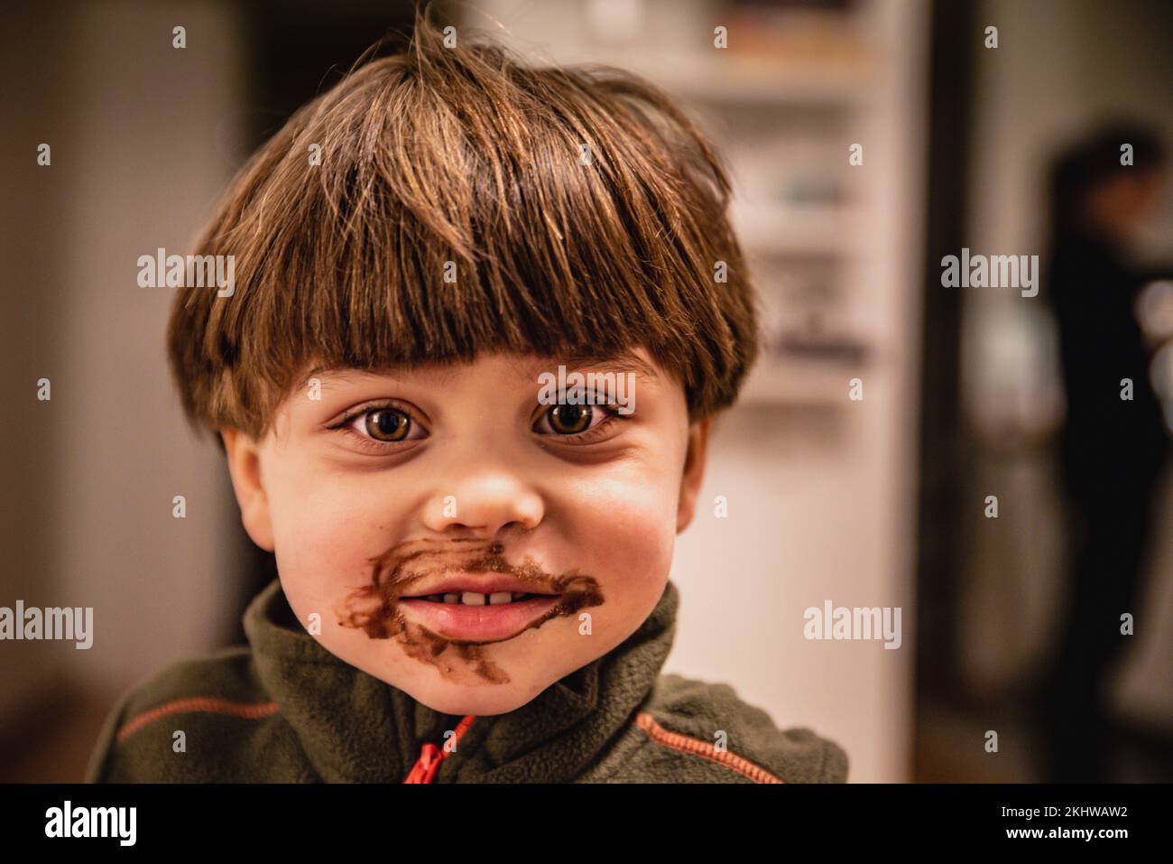 Smily, gai gai avec bob cheveux droits regarde l'appareil photo avec des lèvres sales avec du chocolat. Un enfant heureux et joyeux dans un environnement chaleureux et accueillant est smi Banque D'Images