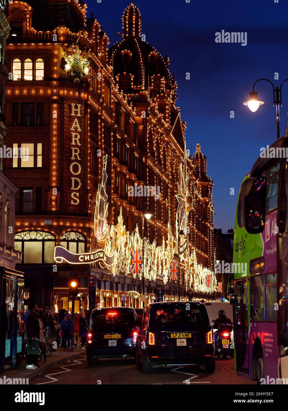 Harrods célèbre grand magasin à Knightsbridge avec une exposition de Noël. Piétons et circulation à l'extérieur, y compris les taxis. Londres. Banque D'Images