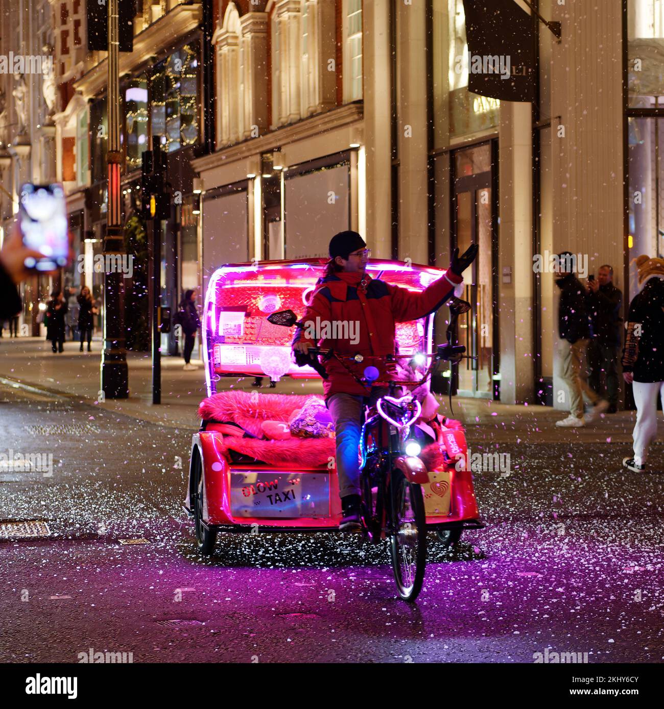 Pediab aka Rickshaw avec des lumières de néon sur une nuit d'hiver dans New Bond Street, comme la fausse neige tombe autour. Londres Banque D'Images