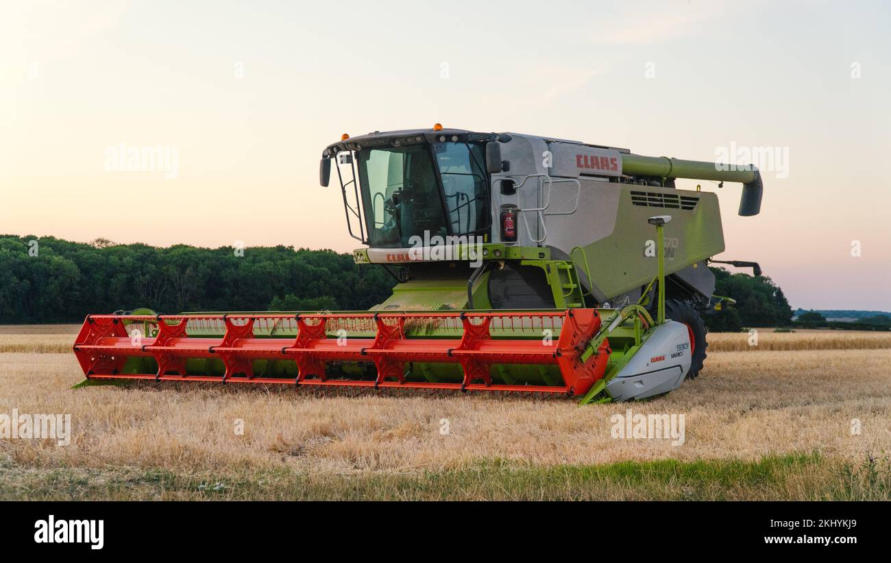 Une moissonneuse-batteuse CLAAS sur une colline au coucher du soleil. Banque D'Images