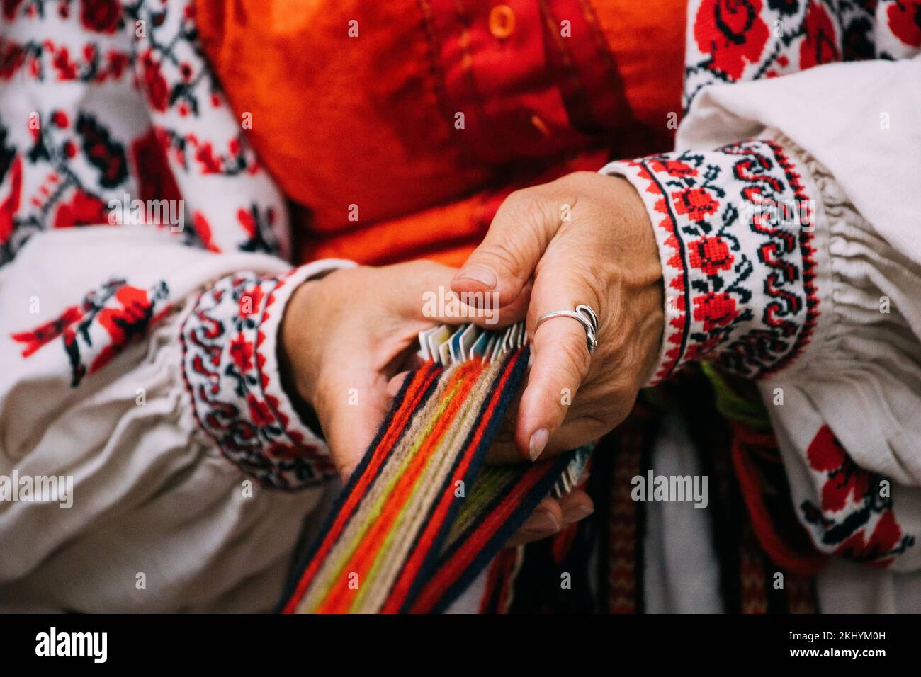 Festival folklorique de Minsk, Biélorussie. Un gros plan du Weaver féminin adulte en vêtements biélorusses brodés traditionnels montre le processus de la ceinture de rotation. Banque D'Images