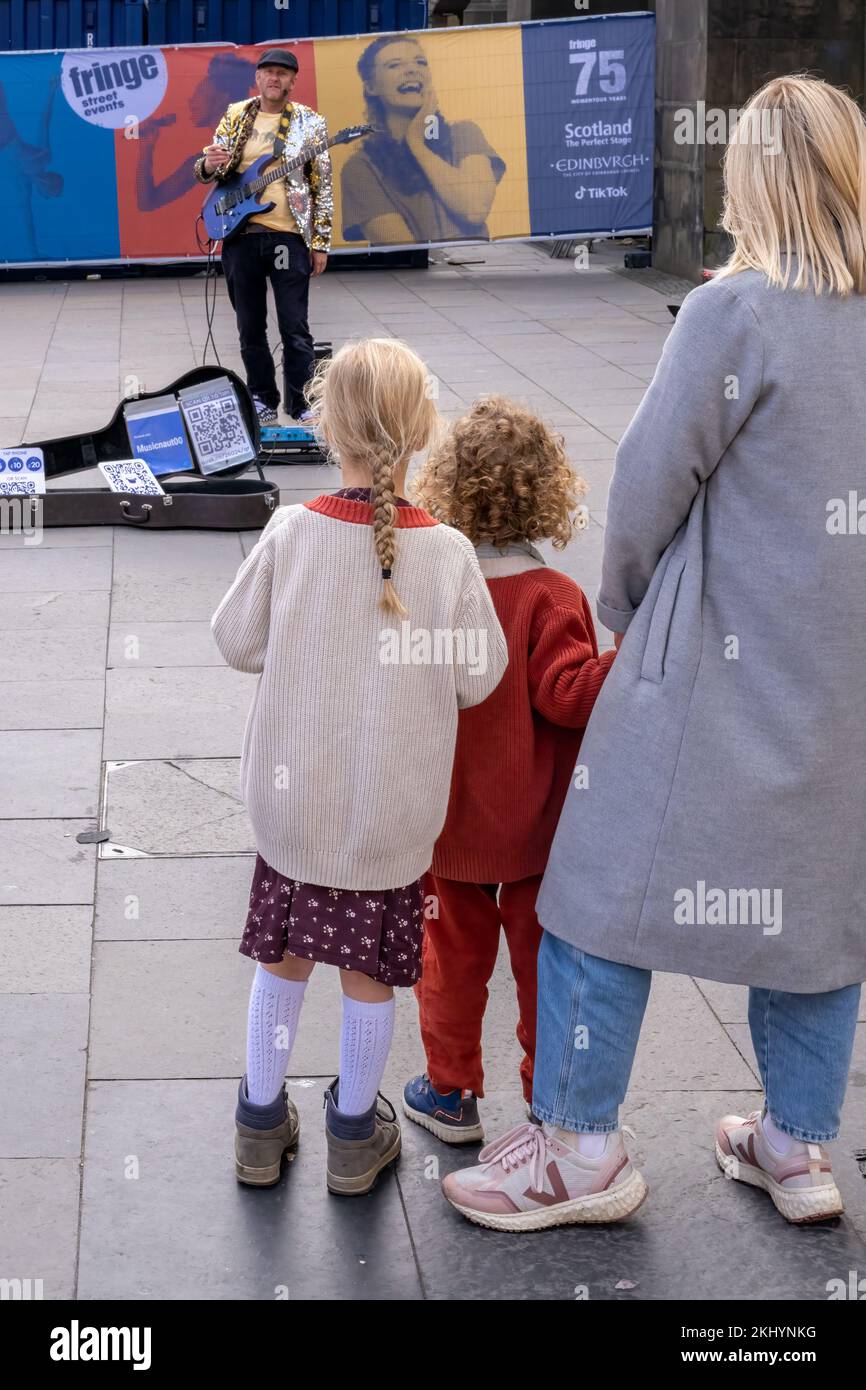 Petite foule. Deux jeunes enfants et leur mère regardent un artiste de rue Edinburgh Fringe commencer son spectacle sur l'historique Royal Mile d'Édimbourg. Banque D'Images