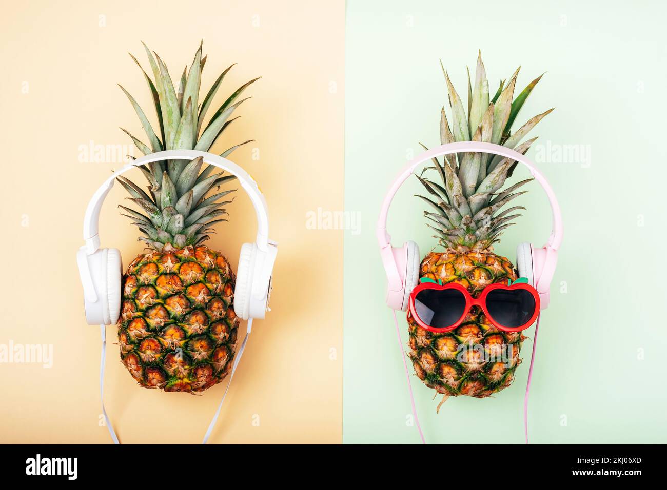 Deux ananas en lunettes de soleil avec écouteurs sur fond vert clair et jaune. Concept d'été. Vue de dessus, plan d'agencement. Banque D'Images