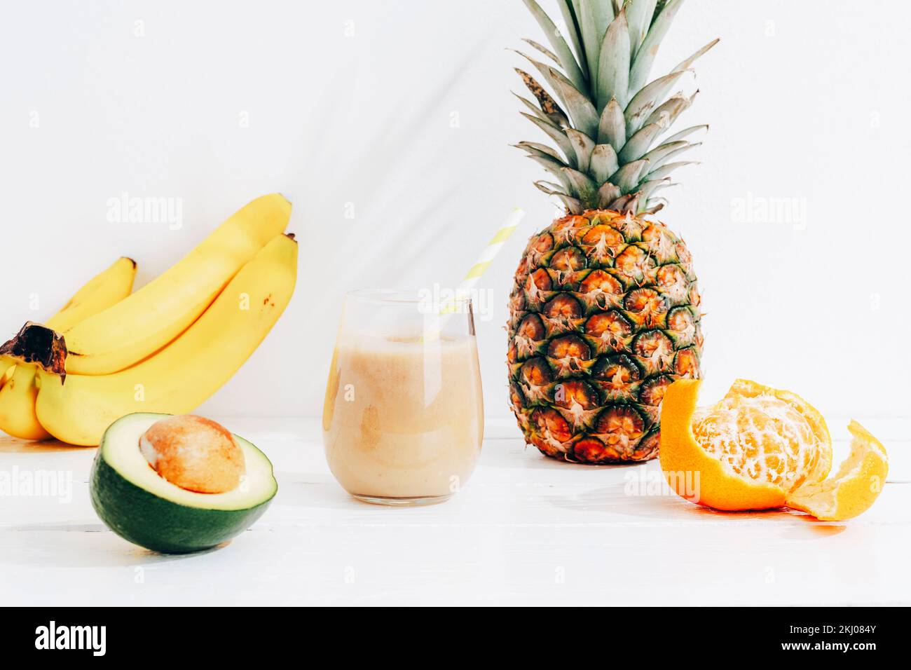 Encore la vie avec des fruits, la banane, l'ananas et l'avocat smoothie sur table en bois blanc au soleil. Concept minimal de diète de détox, boisson de vitamine d'été. Banque D'Images