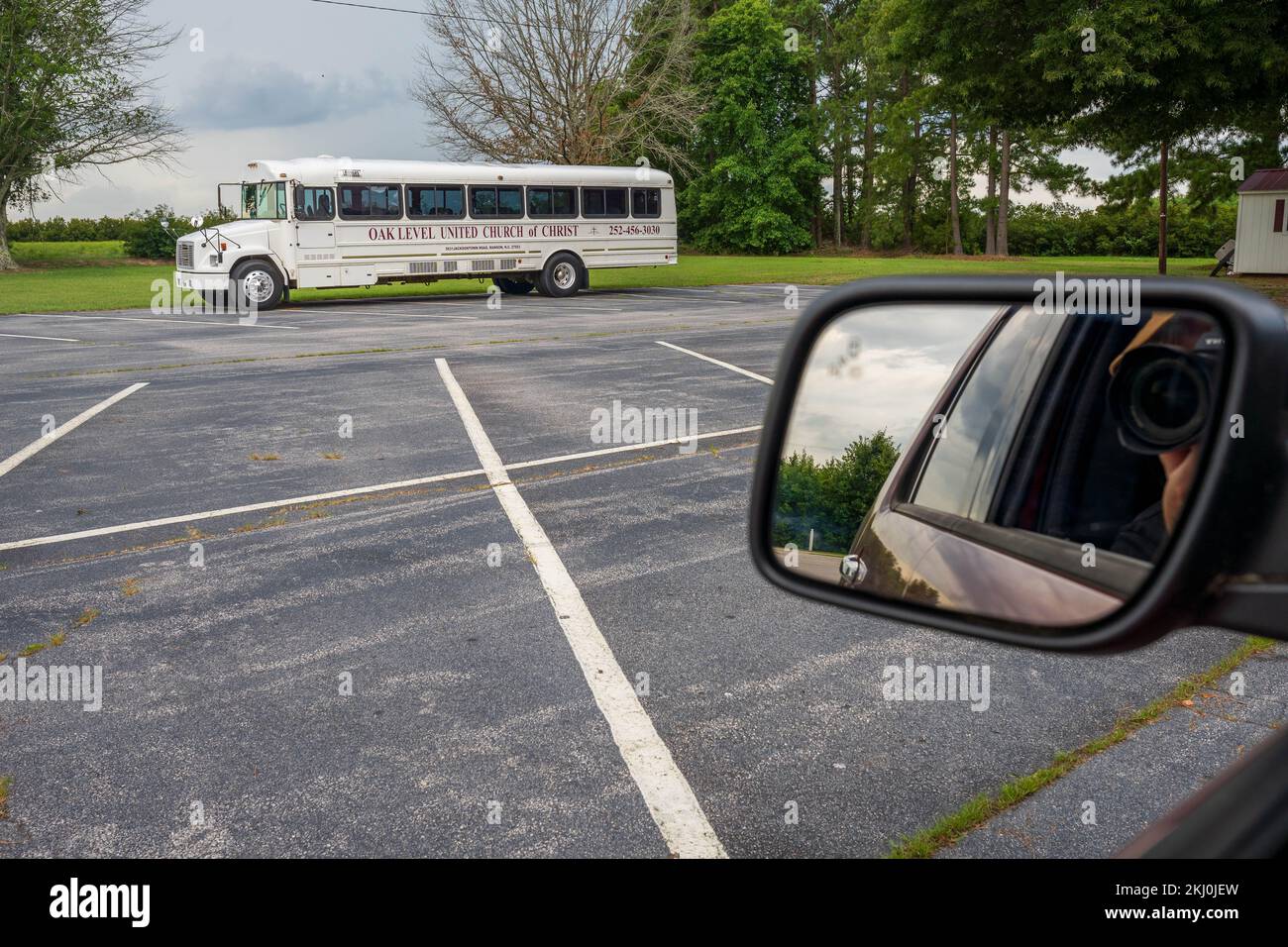 Le photographe prend une photo d'un bus d'église américain blanc de sa voiture dans un parking Banque D'Images
