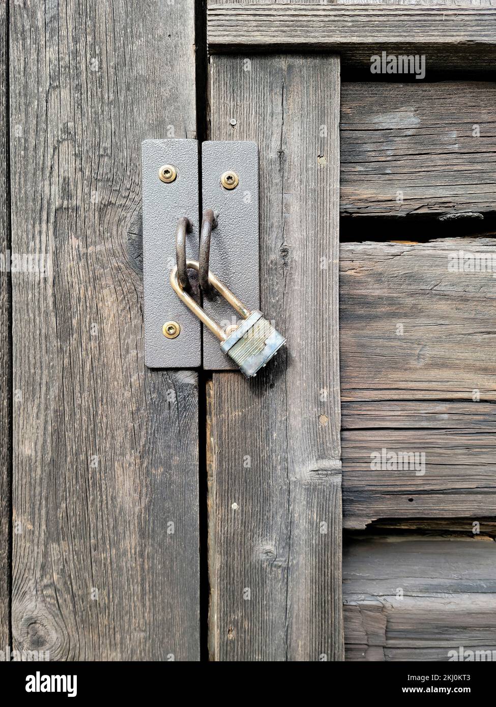 Gros plan d'un cadenas abîmé sur une ancienne porte en bois Banque D'Images