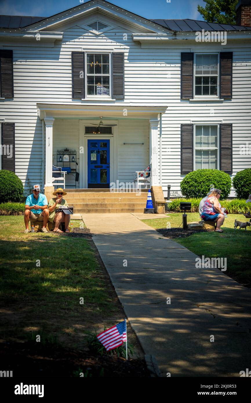 Les gens assis et attendant dans la grande maison de campagne et petit drapeau américain sur le premier plan Banque D'Images
