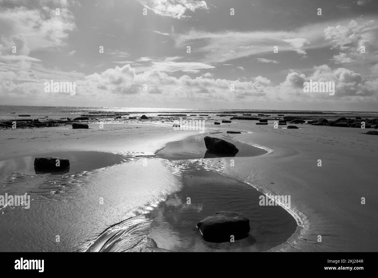 Noir et blanc de piscines de roche sur une belle plage de sable déserte à Lyme Regis Dorset Angleterre côte jurassique Banque D'Images