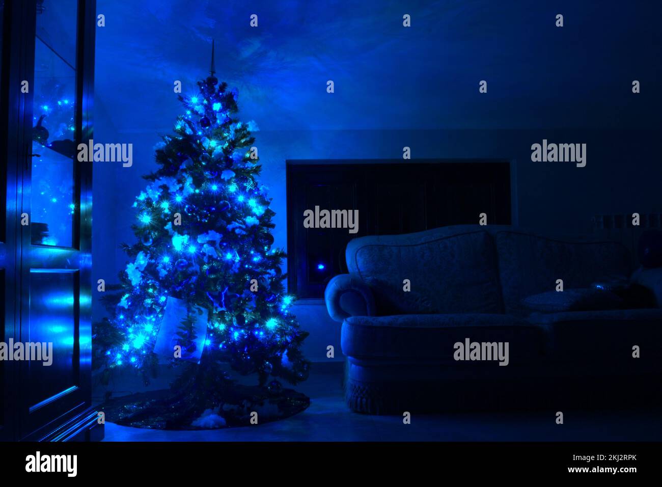 Carte postale avec un sapin de Noël dans une fenêtre avec lumières bleues.carte postale avec sapin de noël avec lumières bleues. Banque D'Images