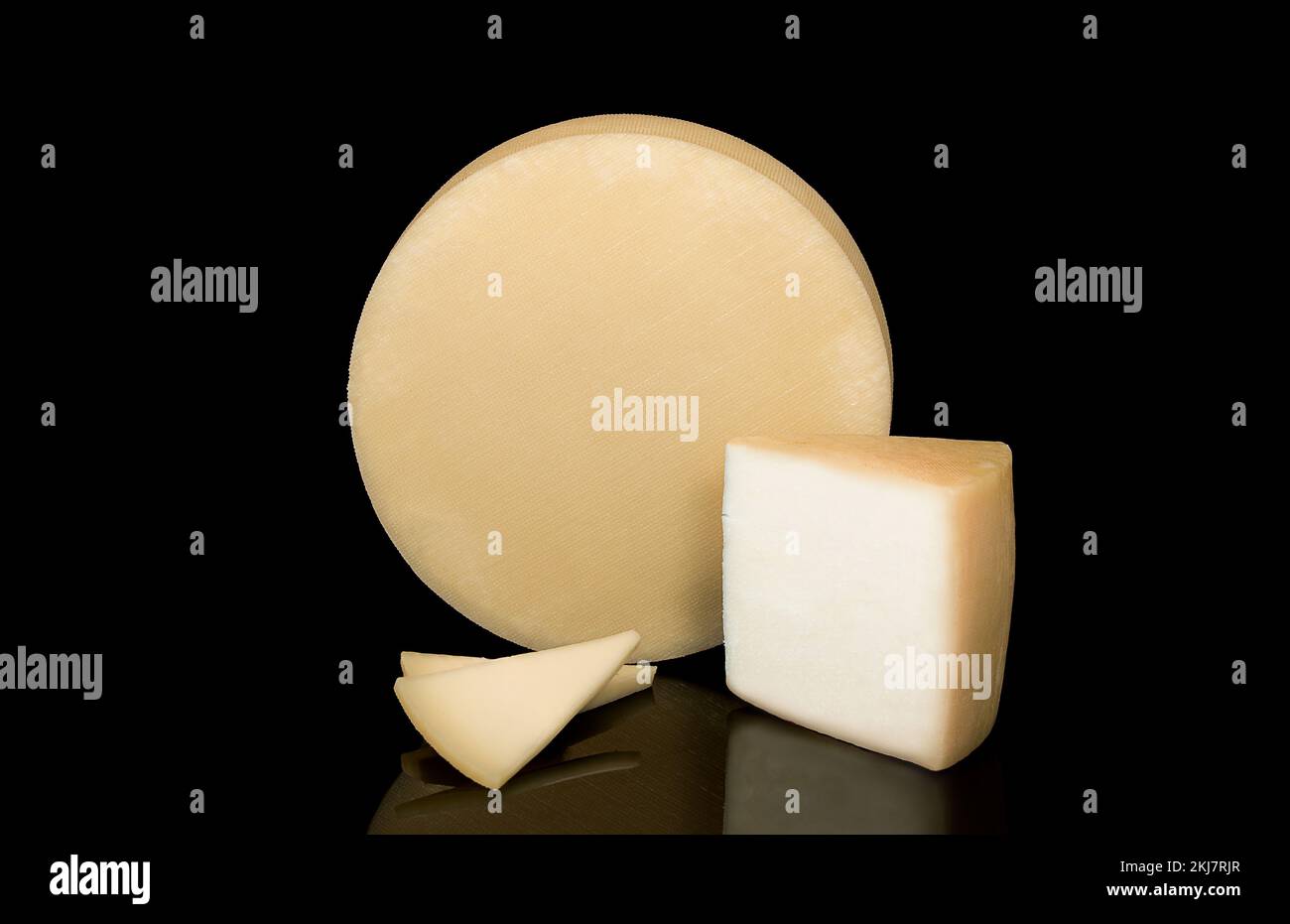Un fromage avec une texture à son arrière isolé sur un fond noir à côté d'un coin et des tranches de fromage. Banque D'Images