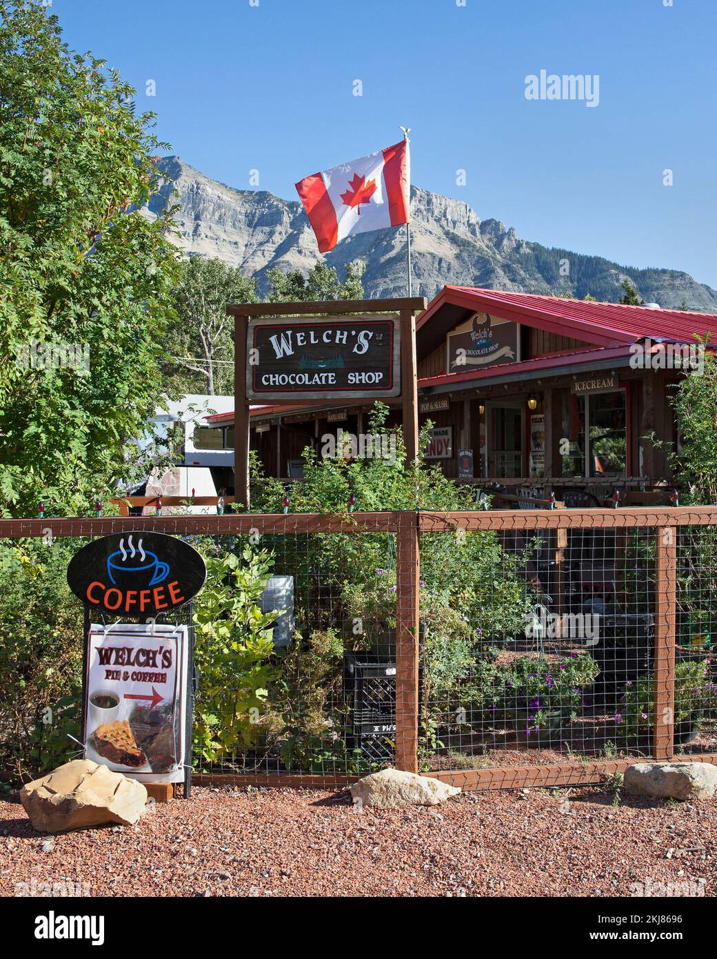 Le magasin de chocolat, le café à tarte et le café de Welch avec drapeau canadien volant dans le parc national des Lacs-Waterton, Alberta, Canada. Banque D'Images