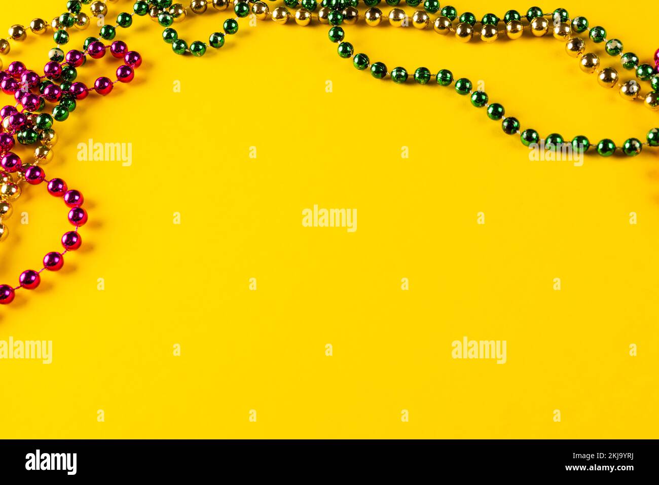 Composition de perles mardi gras colorées sur fond jaune avec espace de copie Banque D'Images