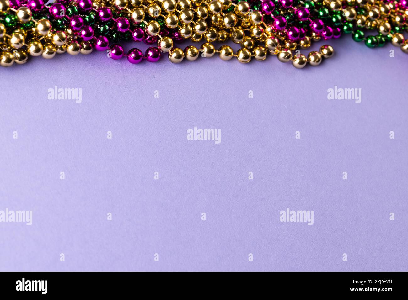 Composition de perles mardi gras colorées sur fond lilas avec espace de copie Banque D'Images