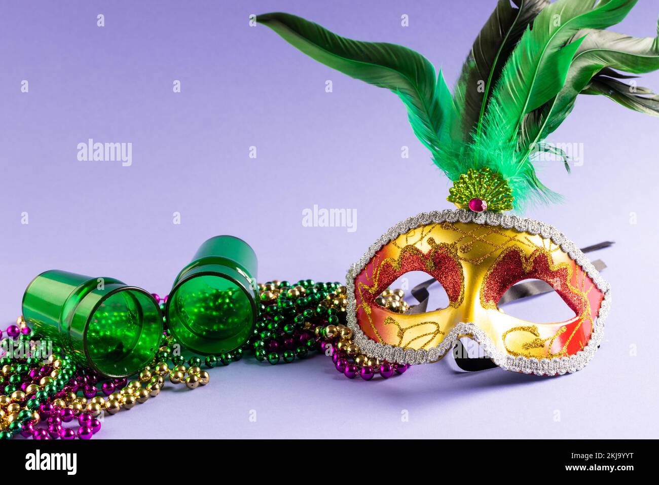 Composition de perles mardi gras colorées, verres à liqueur et masque de carnaval sur bleu avec espace de copie Banque D'Images