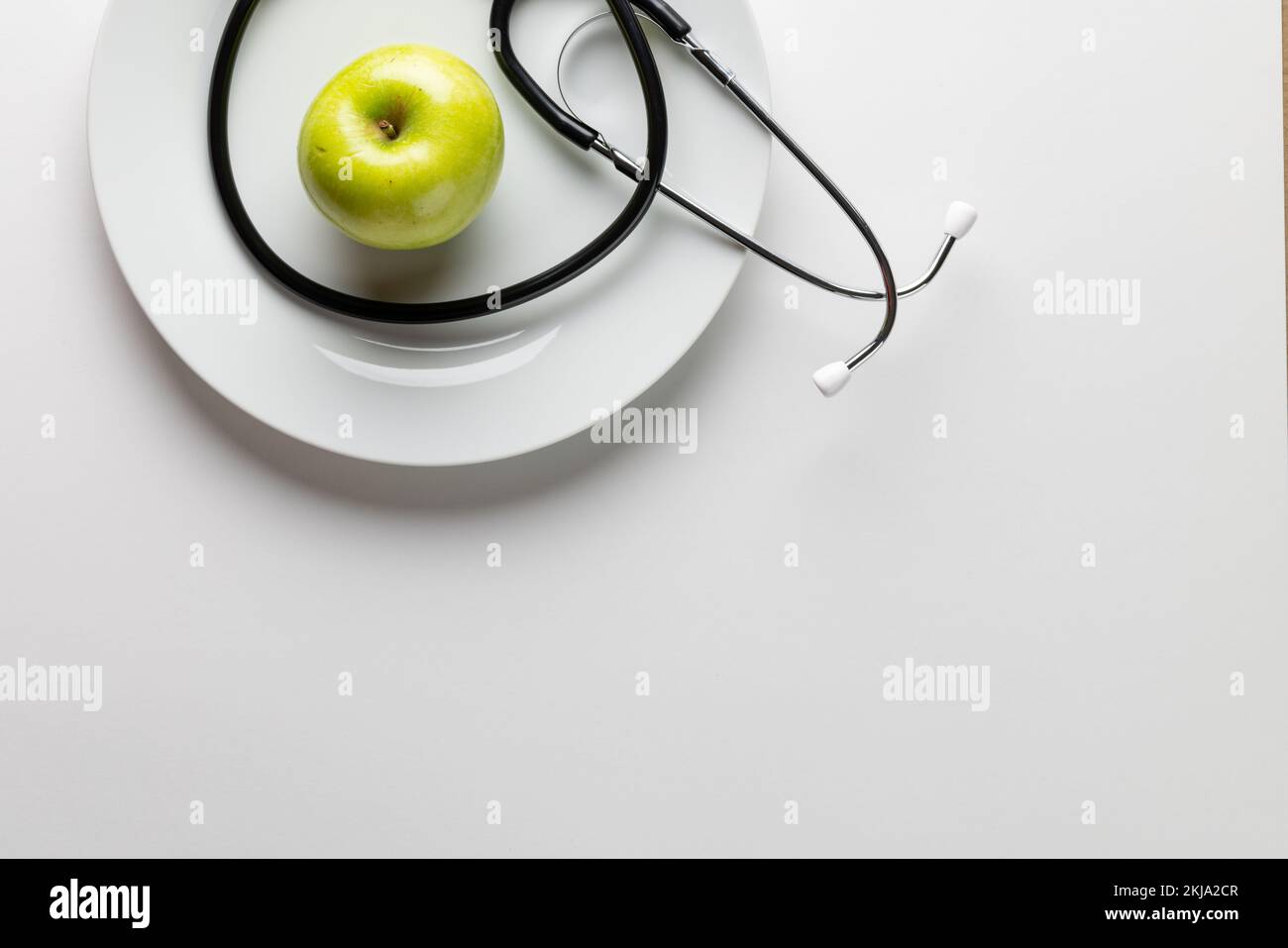 Composition du stéthoscope et de la pomme sur plaque, sur fond blanc avec espace de copie Banque D'Images
