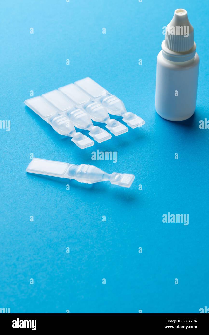 Vertical des caplets de solution saline et du flacon compte-gouttes sur fond bleu avec espace de copie Banque D'Images