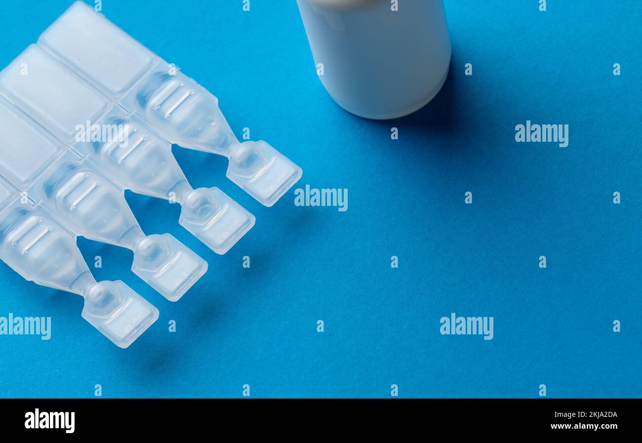 Composition des caplets de solution saline et du flacon compte-gouttes sur fond bleu avec espace de copie Banque D'Images