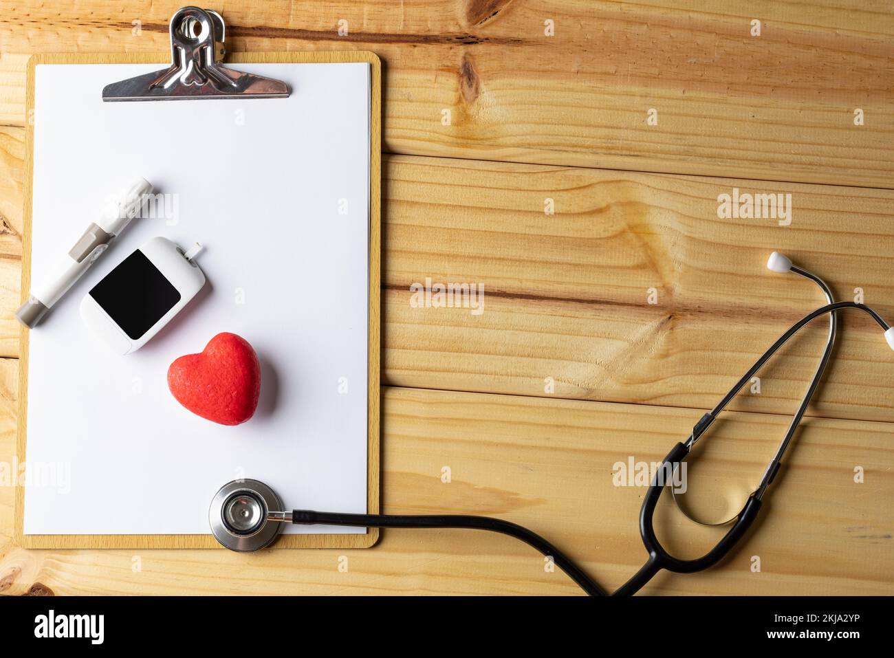 Stéthoscope et presse-papiers avec glucomètre et coeur rouge sur fond en bois avec espace de copie Banque D'Images