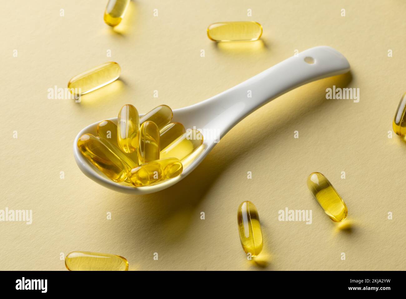 Composition des capsules d'huile et de la cuillère blanche sur fond jaune Banque D'Images