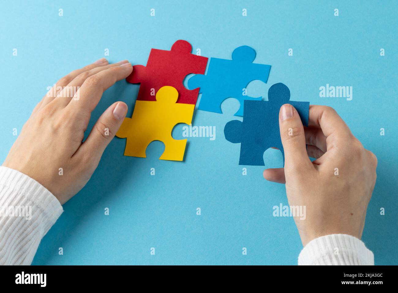 Composition des mains mettant des pièces de puzzle ensemble sur fond bleu avec espace de copie Banque D'Images