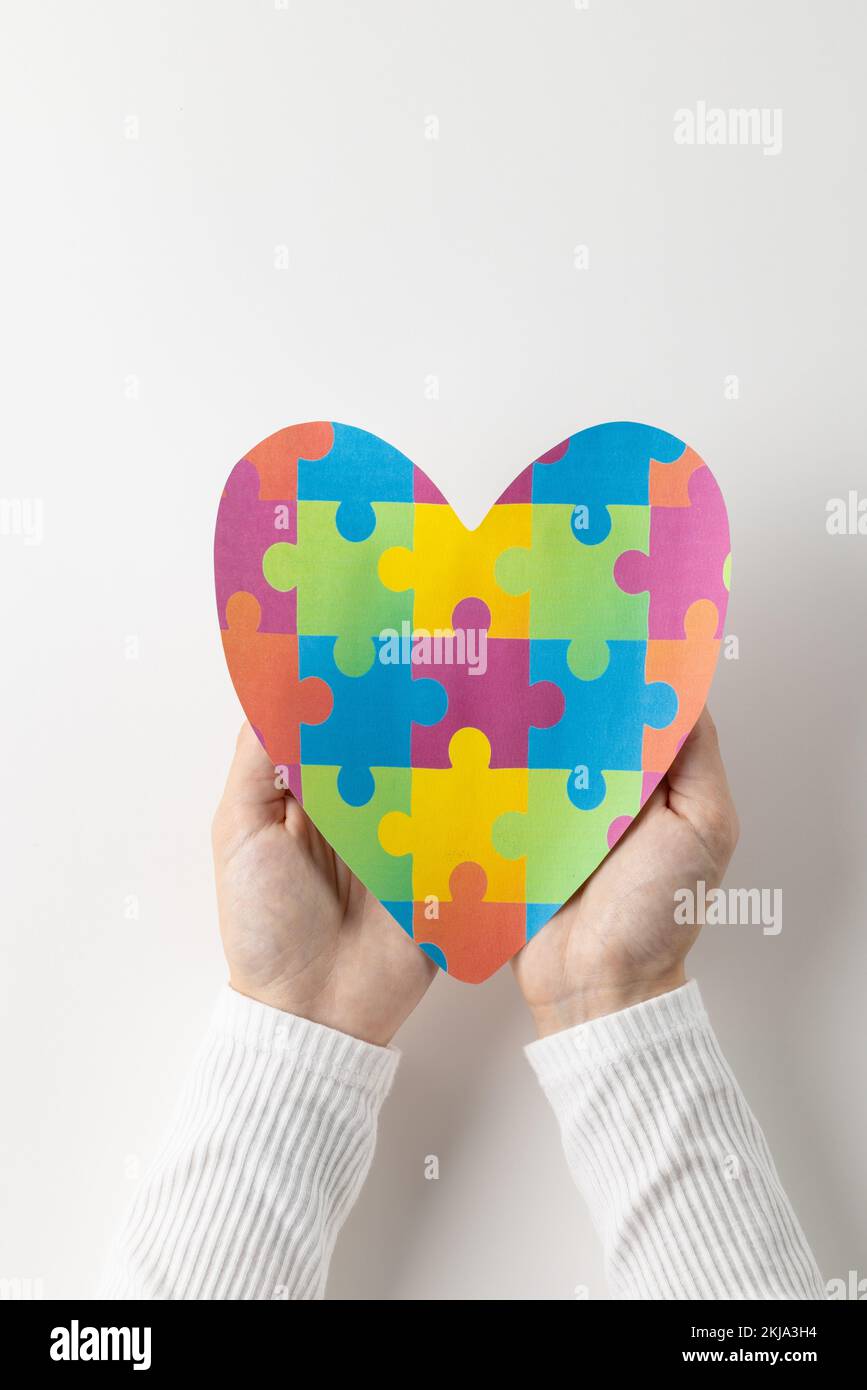 Composition verticale des mains tenant le coeur de puzzle sur fond blanc avec espace de copie Banque D'Images