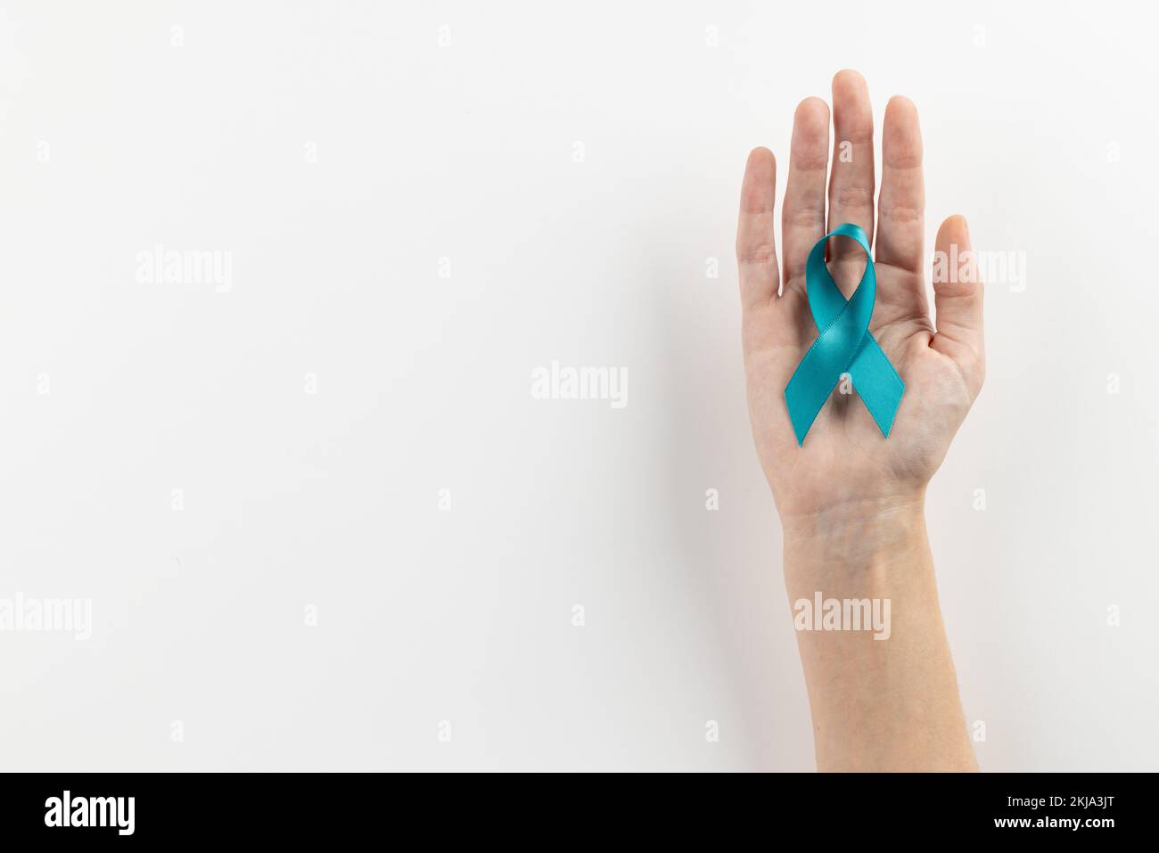 Composition de la main tenant bleu ruban de sensibilisation au cancer de l'ovaire sur fond blanc avec espace de copie Banque D'Images