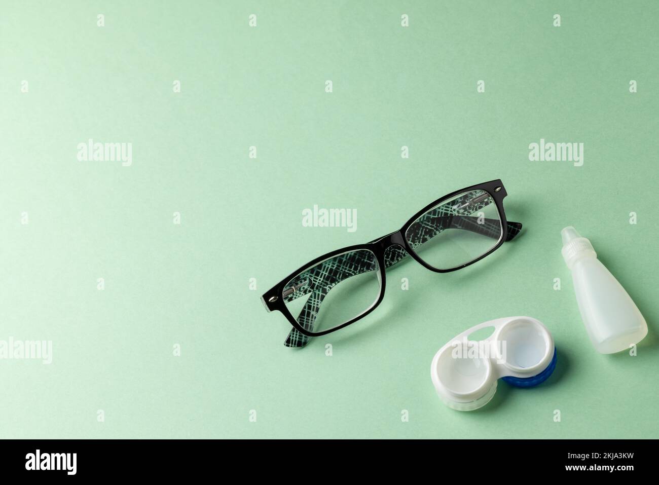 Composition de lunettes avec gouttes pour les yeux et lentilles de contact sur fond vert Banque D'Images