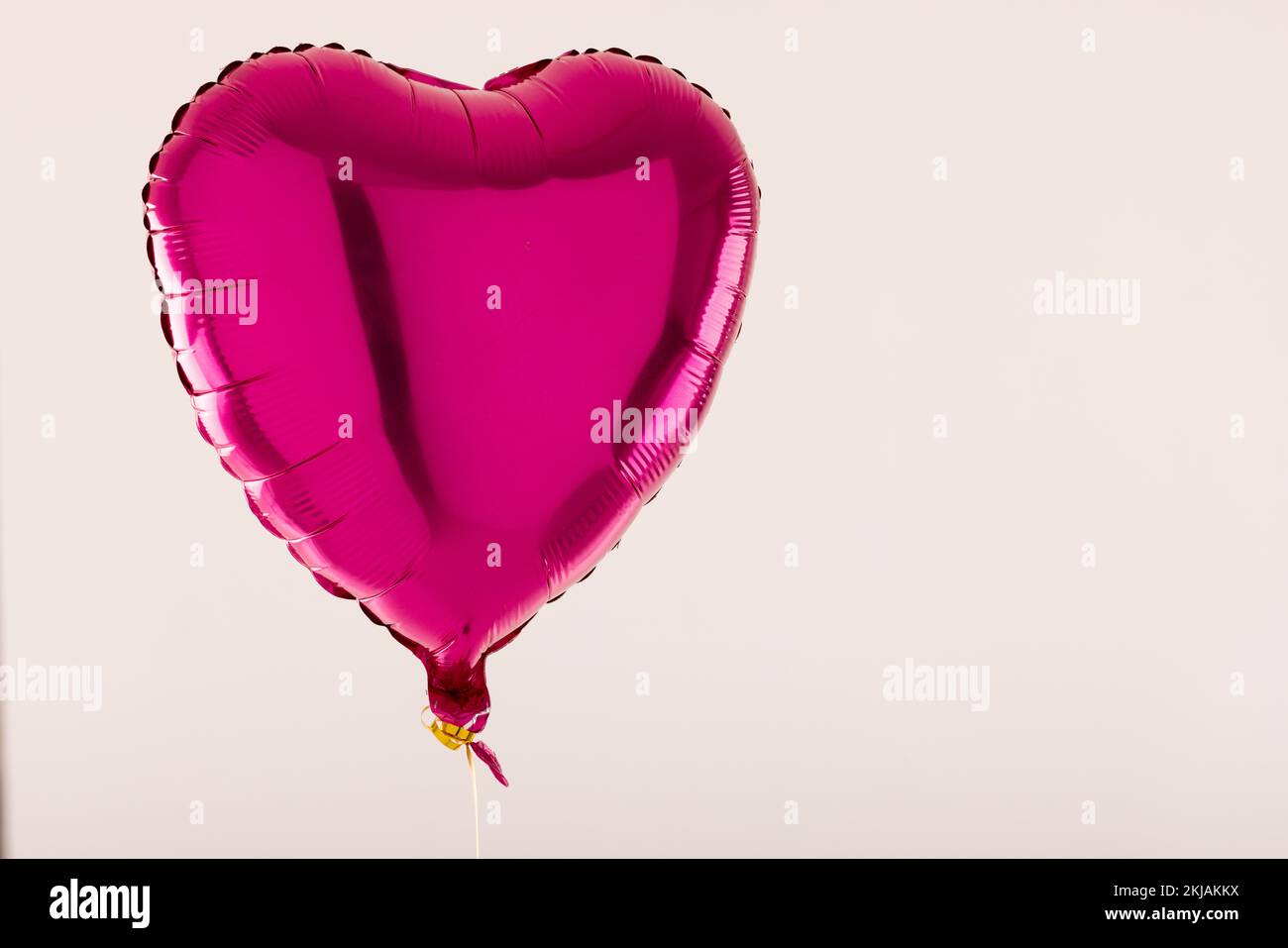 Ballon rose brillant en forme de coeur flottant sur fond blanc avec espace de copie Banque D'Images